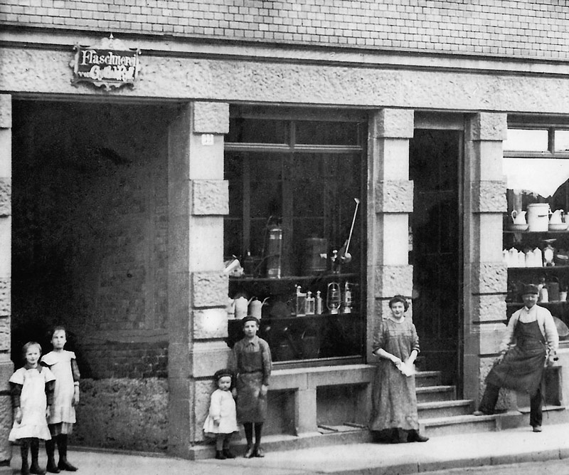 1900 – Haus mit Laden. Es werden zum Teil selbst hergestellte Blechwaren verkauft.